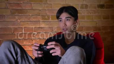 一位年轻的韩国男子在室内用游戏机播放视频游戏的特写镜头